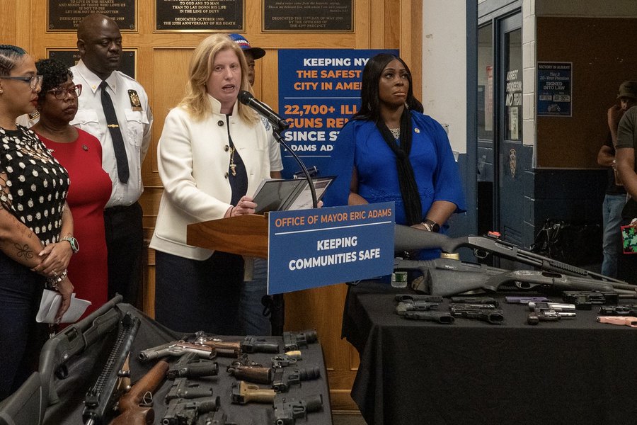 NYPD Commissioner Jessica Tisch speaking at a press conference about gun violence, with firearms displayed on a table.
