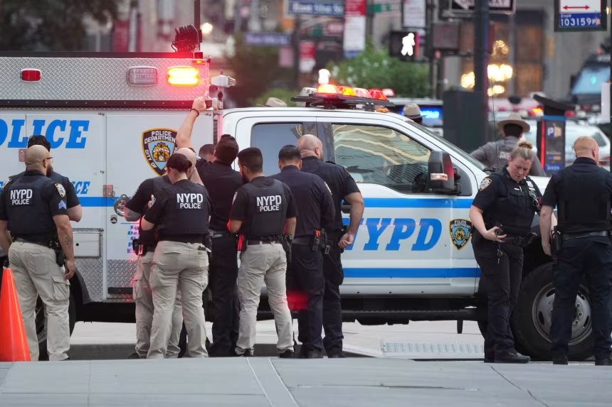NYPD police officers gather around emergency vehicles at the scene of the Midtown Manhattan mass shooting outside 345 Park Avenue.