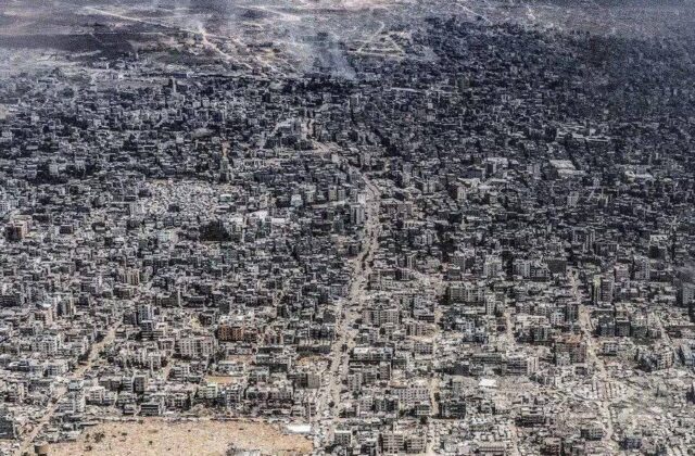 Aerial view of Gaza city destruction showing damaged buildings, smoke, and debris after prolonged conflict.